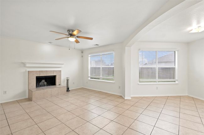Unfurnished living room with a fireplace, a ceiling fan, visible vents, and baseboards | Image 4