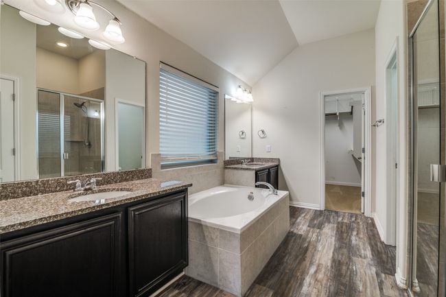 Primary bathroom with a stall shower, lofted ceiling, two vanities, a walk in closet, and a bath | Image 15