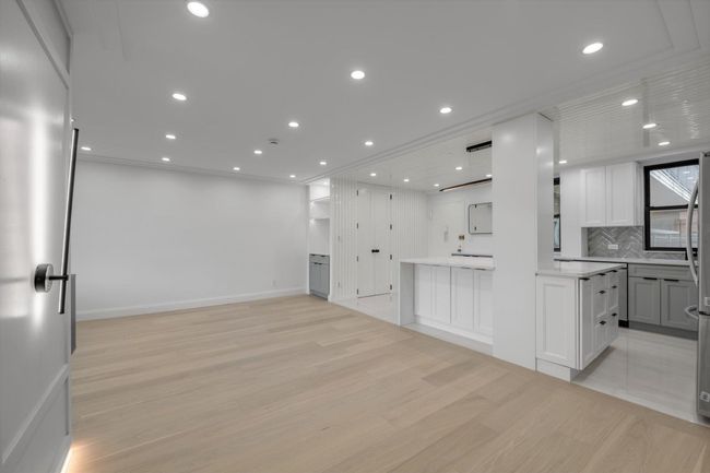 Kitchen featuring light wood-type flooring, open floor plan, decorative backsplash, recessed lighting, and white cabinets | Image 4