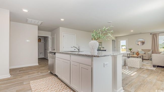 Kitchen featuring sink, white cabinets, a kitchen island with sink, light stone countertops, and light hardwood / wood-style flooring | Image 7