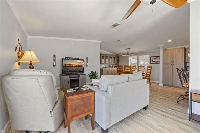 Living room featuring light wood finished floors, a ceiling fan, visible vents, and baseboards | Image 16
