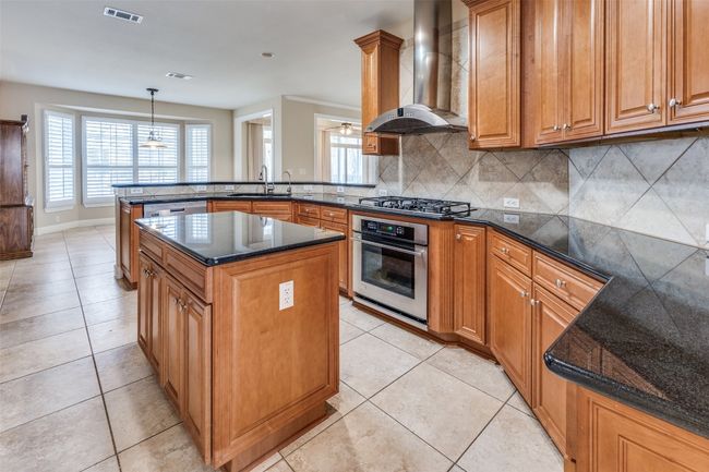 Kitchen with light tile patterned flooring, visible vents, a peninsula, stainless steel appliances, and wall chimney range hood | Image 10