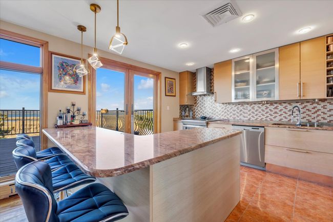 Kitchen with water views and a wealth of natural light, stainless steel appliances, and wall chimney exhaust hood | Image 4