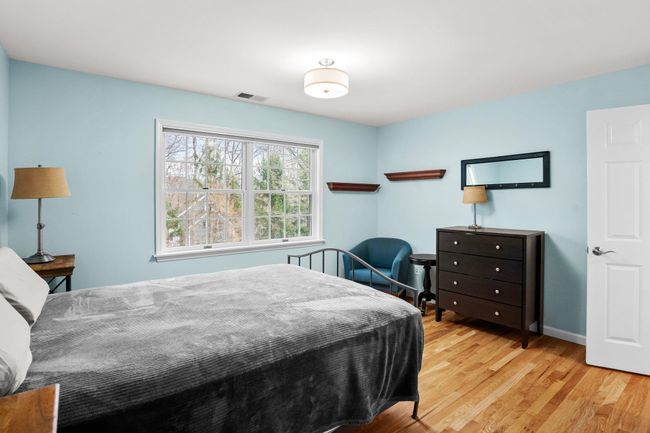 One of three en suite bedrooms on the second floor, this bright and airy space features hardwood floors, a large window with peaceful views, and ample room for both rest and relaxation. | Image 26