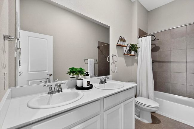 Bathroom featuring shower / bath combo, double vanity, and dark tile patterned floors | Image 30