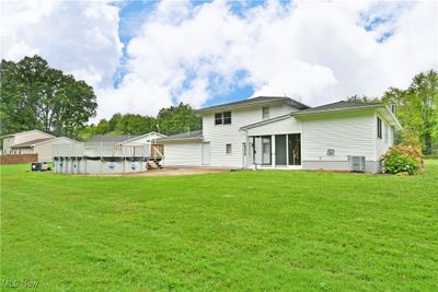 Rear view of house with a patio area, a yard, a covered pool, and central AC | Image 2