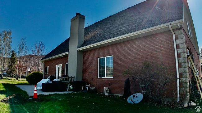 View of side of home with roof with shingles, a chimney, and brick siding | Image 15