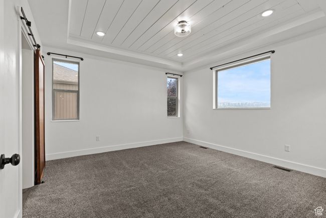 Carpeted empty room with a raised ceiling, recessed lighting, baseboards, and wooden ceiling | Image 14