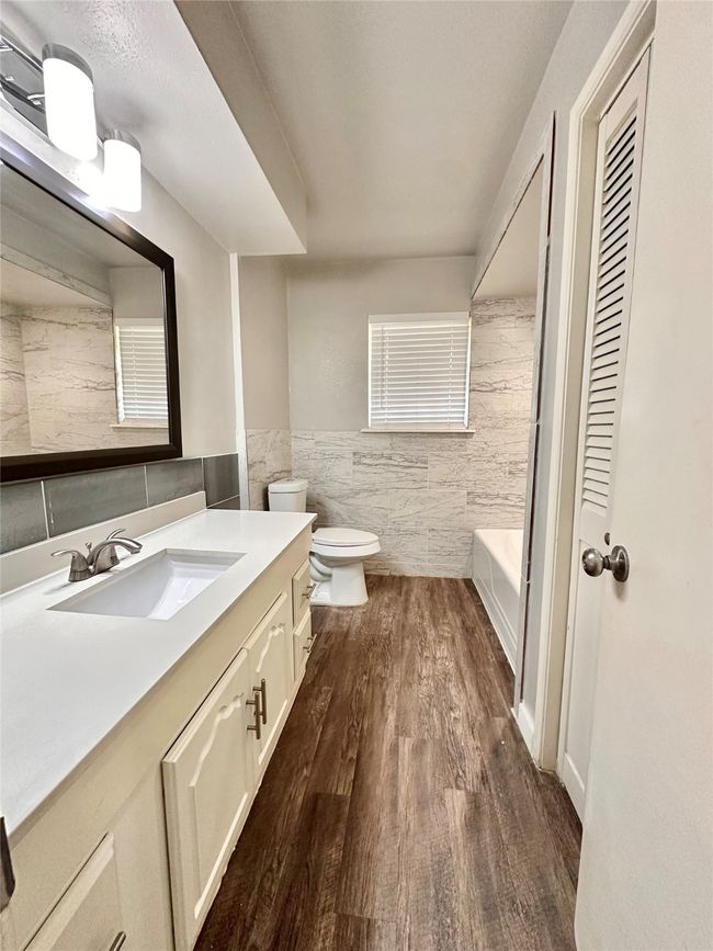 Full bath featuring tile walls, vanity, wood finished floors, and a wainscoted wall | Image 27