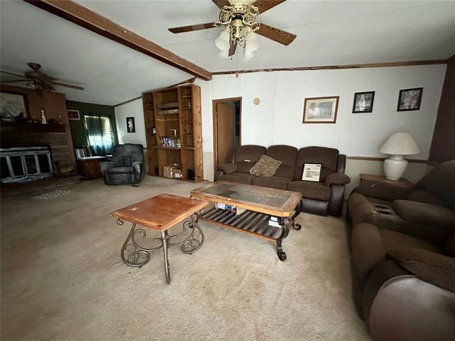 Spacious living room with cozy seating, ceiling fans, a fireplace, and built-in shelving. Perfect for relaxing and entertaining. | Image 5