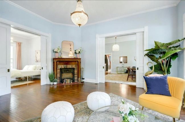 Living room with wood finished floors, ornamental molding, and a brick fireplace | Image 5