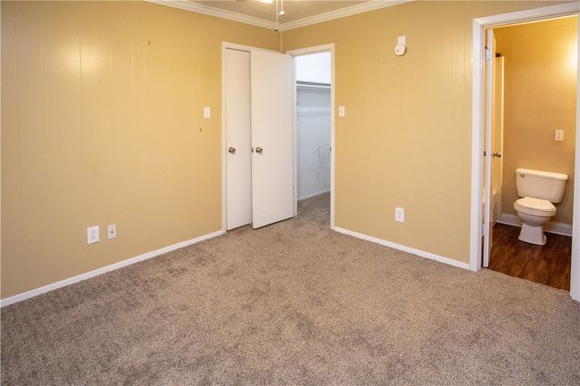 Unfurnished bedroom featuring crown molding, carpet floors, a closet, and connected bathroom | Image 7