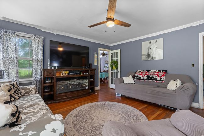 Living room with ceiling fan, wood finished floors, and crown molding | Image 10