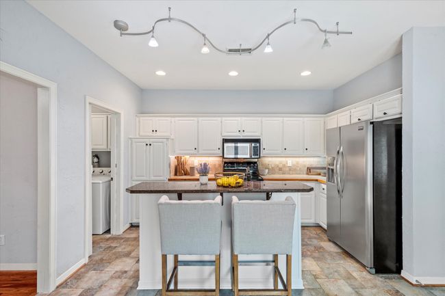 Kitchen featuring appliances with stainless steel finishes, white cabinets, tasteful backsplash, stone finish flooring, and recessed lighting | Image 11