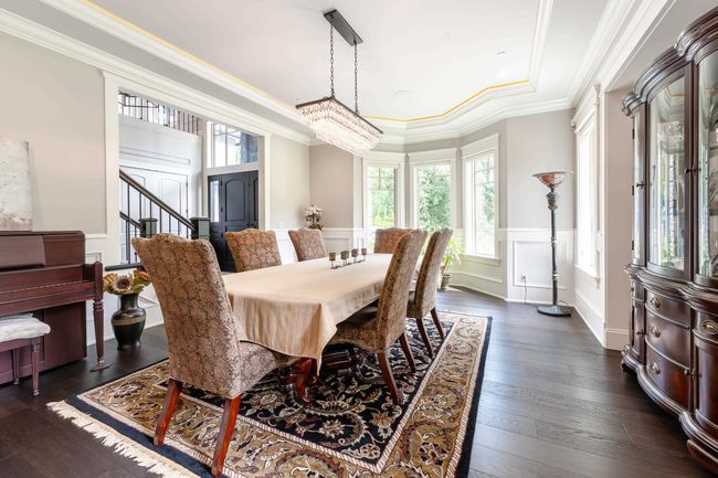 Dining area featuring wainscoting, a decorative wall, dark wood-type flooring, ornamental molding, and stairway | Image 11