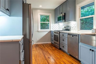 Kitchen featuring stainless steel appliances, decorative backsplash, gray cabinets, and light hardwood / wood-style flooring | Image 2