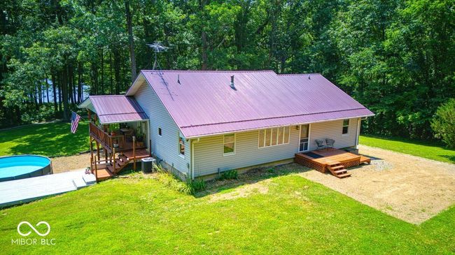 back of house featuring a yard, a metal roof, an outdoor pool, and a wooden deck | Image 12