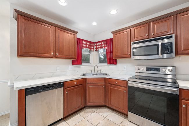 Kitchen with light countertops, recessed lighting, appliances with stainless steel finishes, a sink, and light tile patterned floors | Image 7