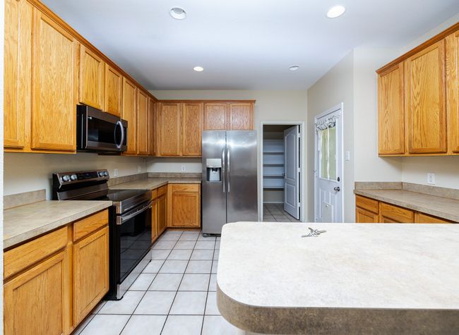 Kitchen with stainless steel appliances, light tile patterned floors, light countertops, and recessed lighting | Image 13