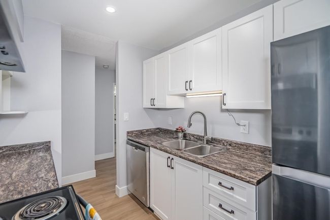 Kitchen featuring stainless steel appliances, a sink, light wood-style floors, white cabinetry, and recessed lighting | Image 7