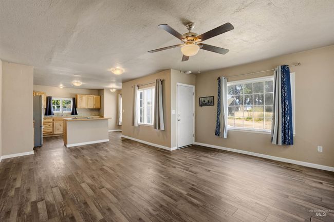 Unfurnished living room featuring a textured ceiling, plenty of natural light, dark wood-style flooring, and a ceiling fan | Image 5