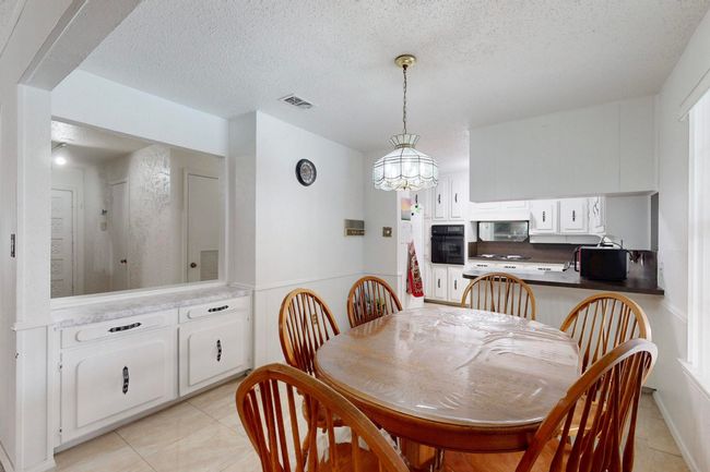 Dining room with light tile patterned flooring, visible vents, a chandelier, and a textured ceiling | Image 10
