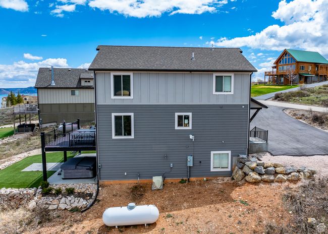 Back of property featuring board and batten siding, a patio, a shingled roof, and a wooden deck | Image 51