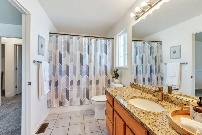 Full bath featuring vanity, toilet, a shower with shower curtain, and tile patterned flooring | Image 9