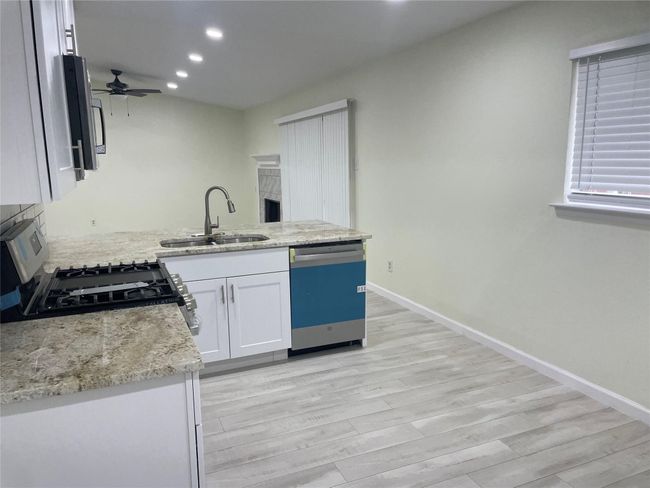 Kitchen with dishwasher, a sink, stainless steel range with gas cooktop, ceiling fan, and white cabinetry | Image 19