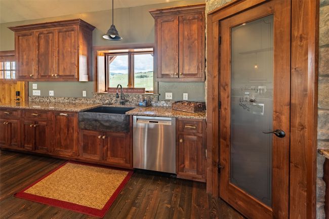 Kitchen with dishwasher, a sink, dark wood-type flooring, light stone countertops, and pendant lighting | Image 16