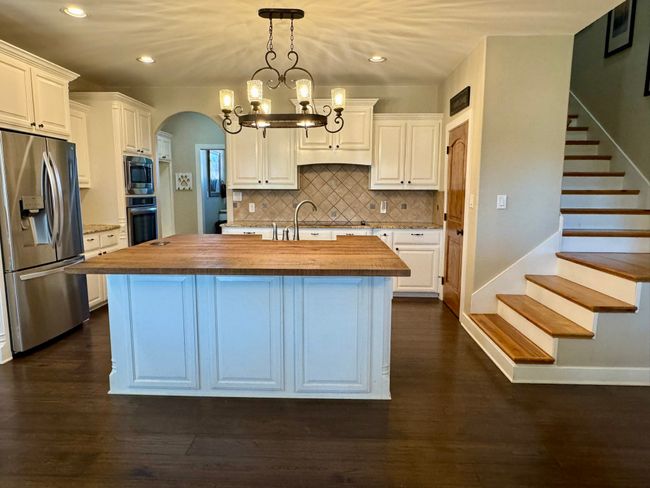 Kitchen featuring butcher block counters, appliances with stainless steel finishes, and white cabinets | Image 9