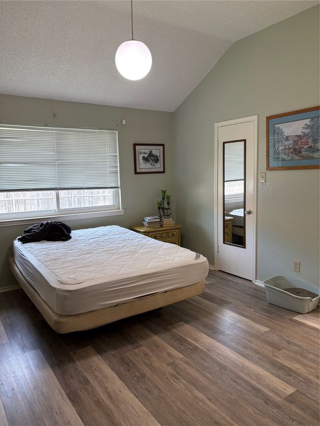 Bedroom featuring wood finished floors, lofted ceiling, a textured ceiling, and baseboards | Image 7