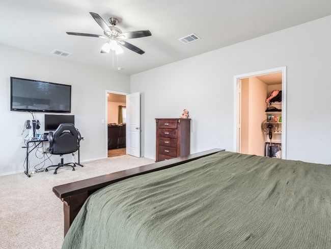 Carpeted bedroom with baseboards, visible vents, a walk in closet, and a ceiling fan | Image 17