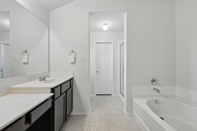Bathroom featuring tile patterned floors, vanity, a bath, baseboards, and a stall shower | Image 31