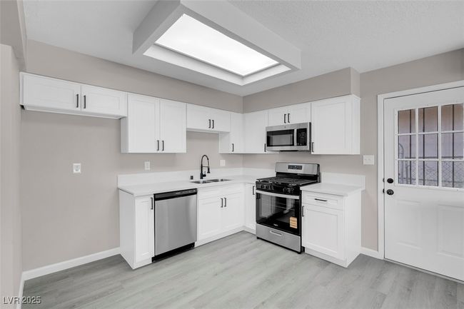 Kitchen featuring baseboards, appliances with stainless steel finishes, a sink, and light wood-style flooring | Image 12