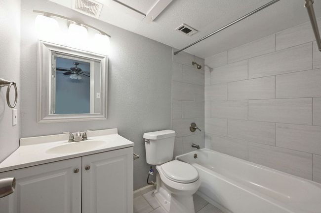 Full bathroom featuring shower / bath combination, vanity, light tile patterned flooring, and a textured wall | Image 18