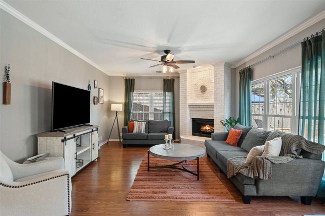 Living room featuring ornamental molding, baseboards, dark wood finished floors, a ceiling fan, and a fireplace | Image 18