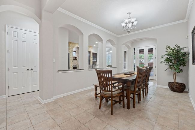 Dining room with light tile patterned floors, crown molding, a chandelier, and baseboards | Image 9