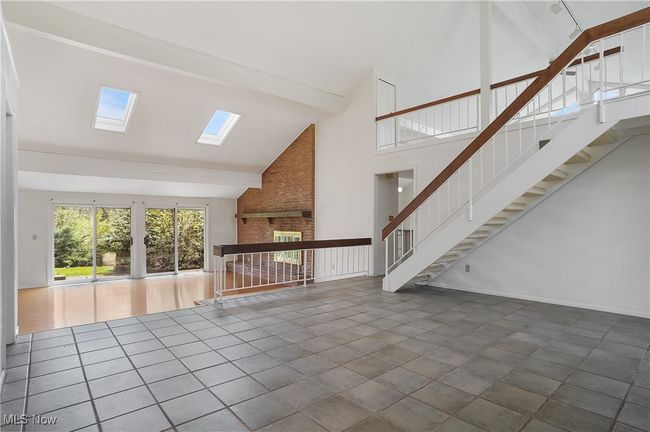 Unfurnished living room with beamed ceiling, stairway, a skylight, and high vaulted ceiling | Image 6