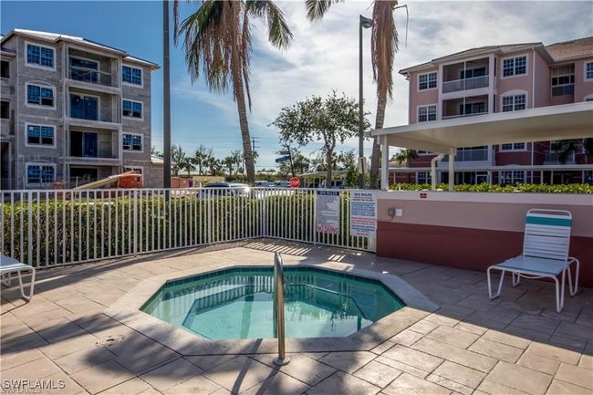 View of swimming pool with a community hot tub and fence | Image 24
