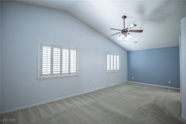 Carpeted spare room featuring a ceiling fan, visible vents, lofted ceiling, and baseboards | Image 18