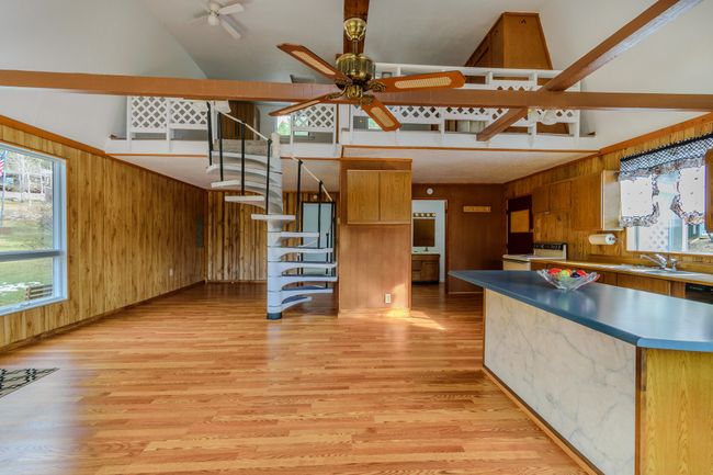 Kitchen with white electric range oven, wooden walls, light wood-type flooring, and high vaulted ceiling | Image 27