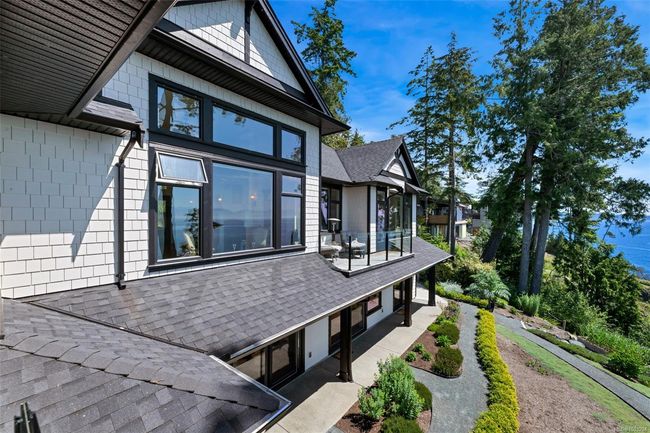 View of home's exterior with a shingled roof, a balcony, and a patio area | Image 74