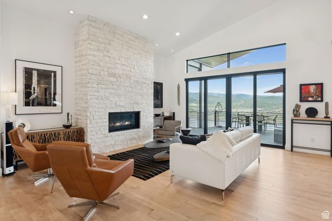 Living room featuring high vaulted ceiling, a stone fireplace, light wood-type flooring, and recessed lighting | Image 12