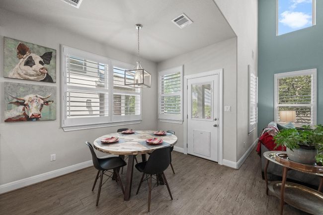 Dining/breakfast nook space with wood finished floors and a chandelier leading to back patio. | Image 15