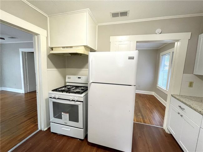 Kitchen with visible vents, under cabinet range hood, white appliances, and dark wood-style floors | Image 6