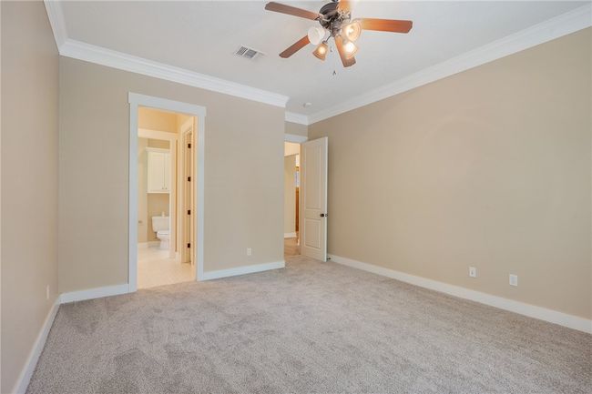 Unfurnished bedroom featuring crown molding, carpet, baseboards, connected bathroom, and ceiling fan | Image 19