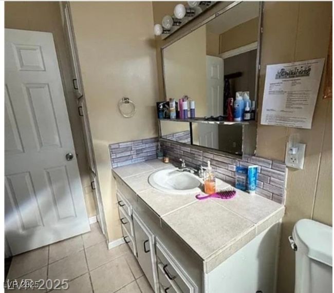 Bathroom with toilet, decorative backsplash, tile patterned flooring, and vanity | Image 7