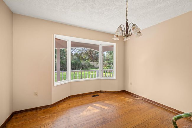 Unfurnished room featuring hardwood / wood-style floors, a chandelier, baseboards, and a textured ceiling | Image 18