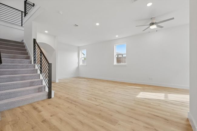 Unfurnished living room with light wood-style floors, stairway, ceiling fan, baseboards, and recessed lighting | Image 14